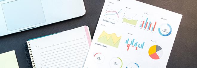 Laptop, notebook, and charts on a table